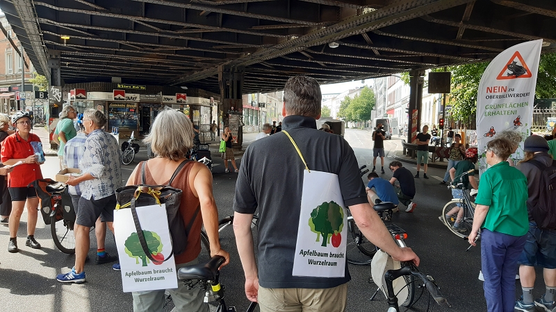 Personen mit AbW Plakaten stehen mit Fahrrad unter der Sternbrücke Altona